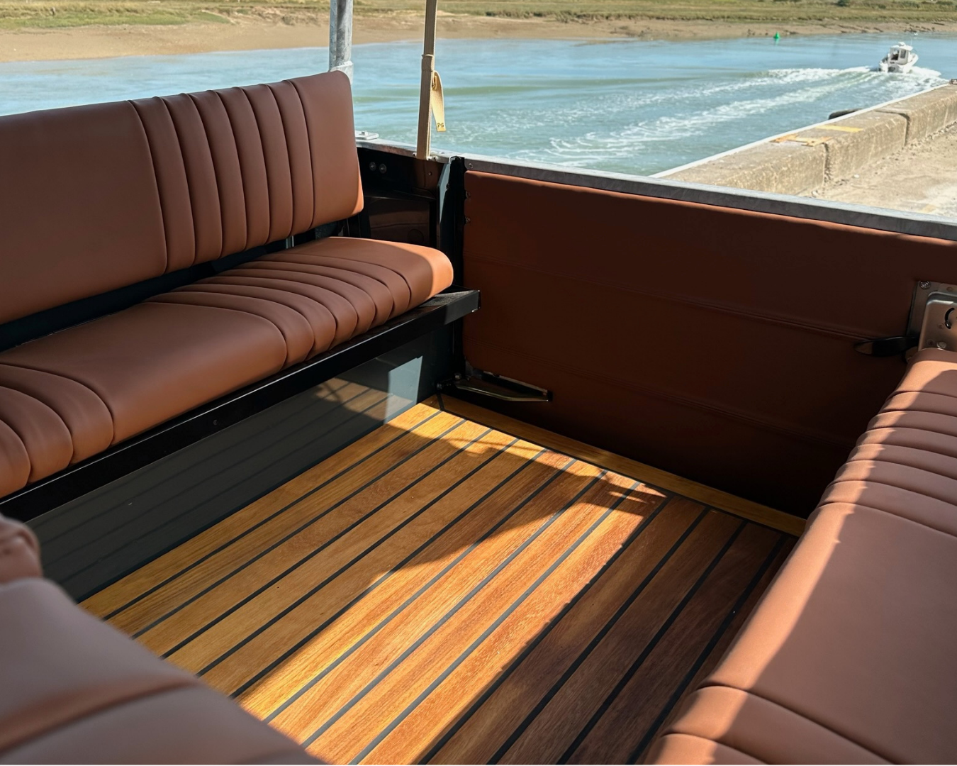 Iroko wood deck flooring and rear bench seats in a Land Rover Defender, moored beside the Rye harbour estuary