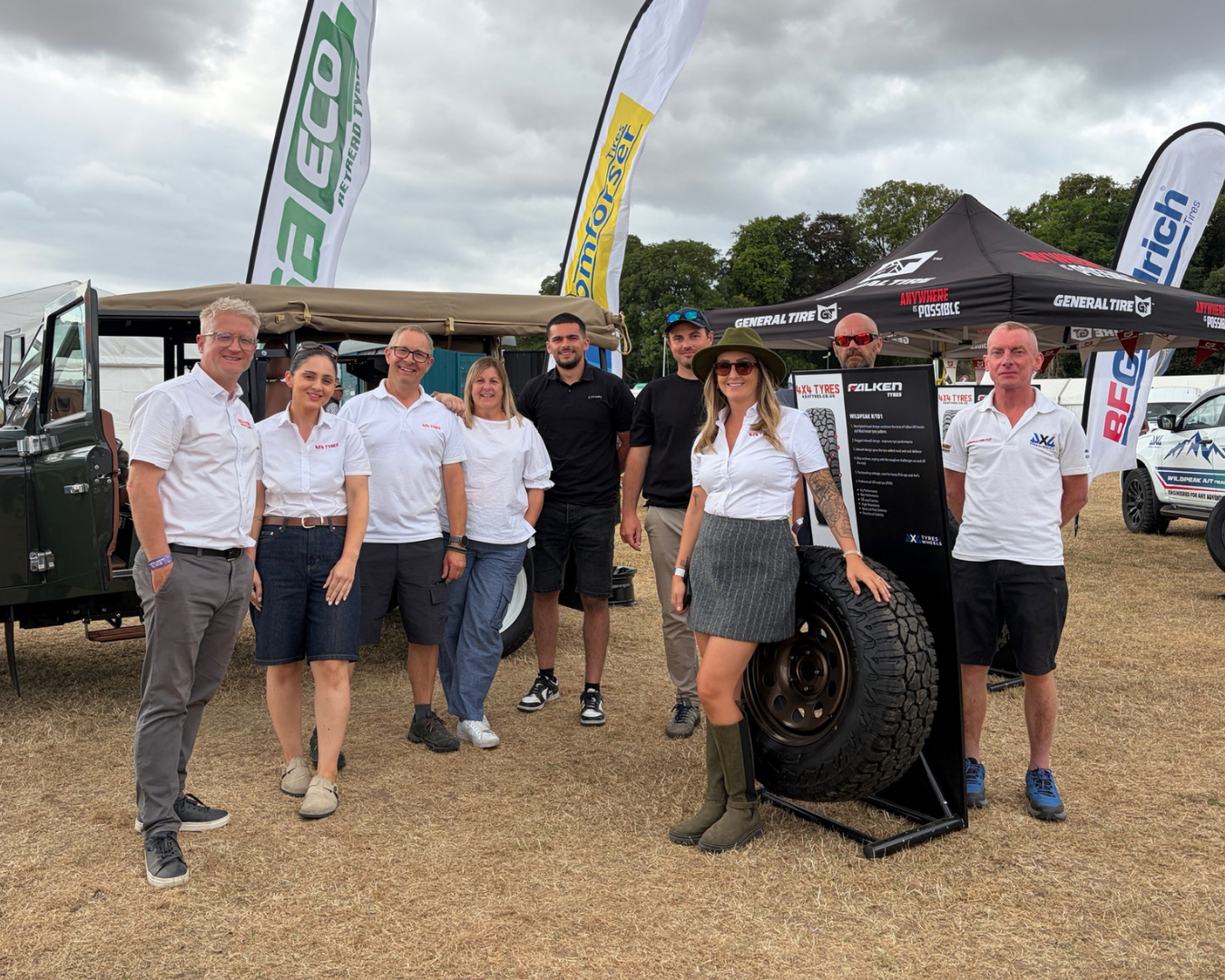 LUCARI and 4x4 Tyres team members posing together at The Game Fair event stand, with tyre displays and branded flags behind them.