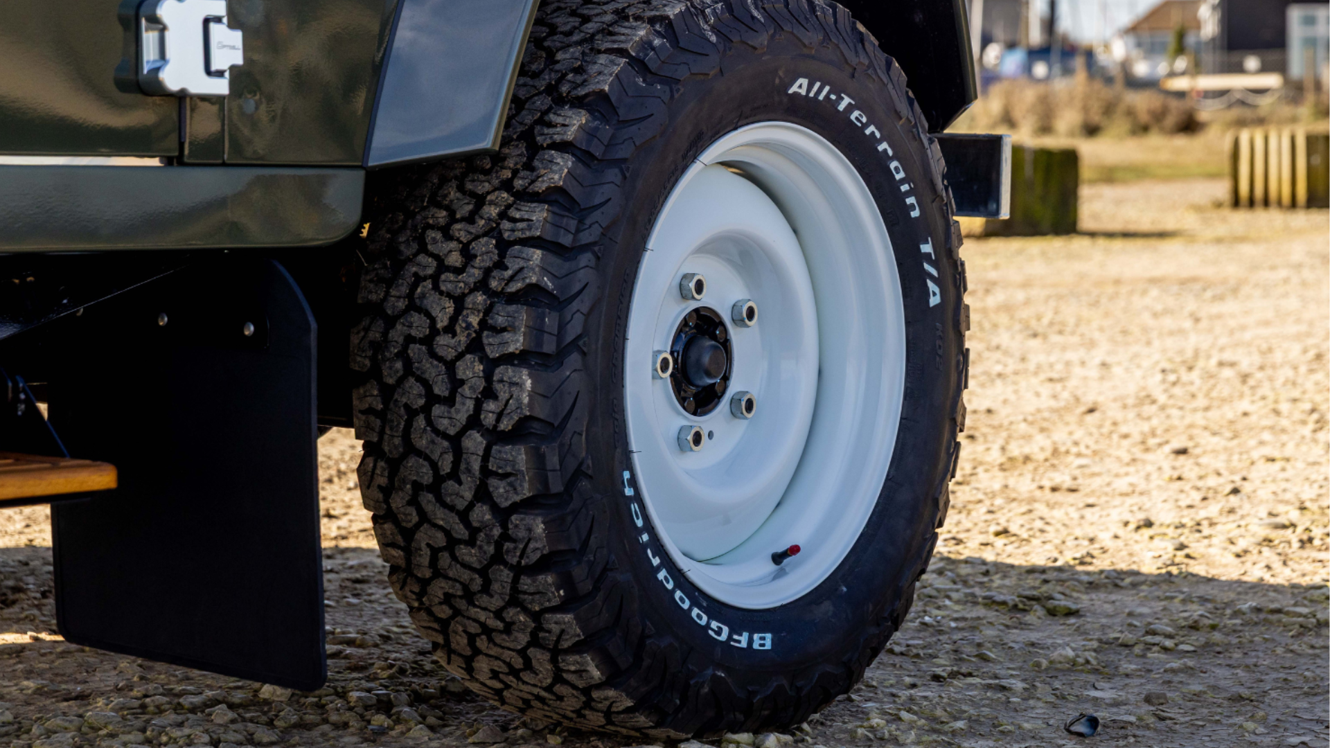 Close-up of a white steel wheel and BFGoodrich All-Terrain tyre on a green Defender.