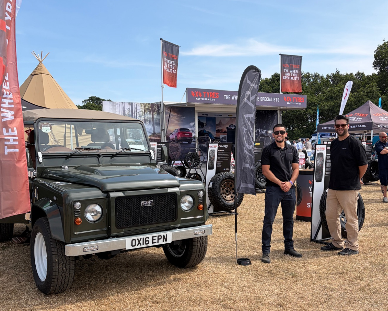 LUCARI Black Olive Green Land Rover Defender 110 parked at The Game Fair alongside two LUCARI team members near the 4x4 Tyres exhibition stand.