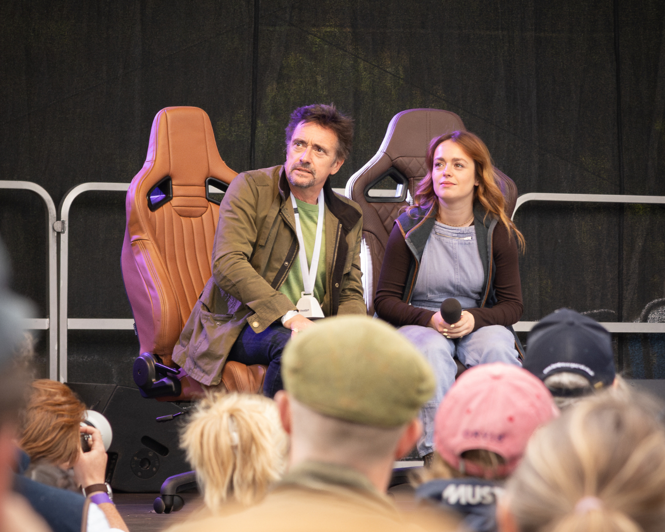 Richard Hammond and Izzy Hammond sitting on LUCARI Leather office chairs on a stage in front of a crowd.