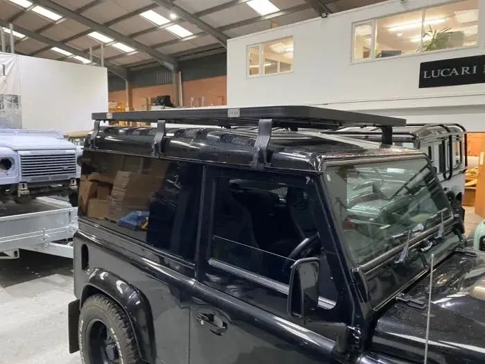Black Defender 90 in the LUCARI workshop with a black LUCARI Defender 90 roof rack fitted on top