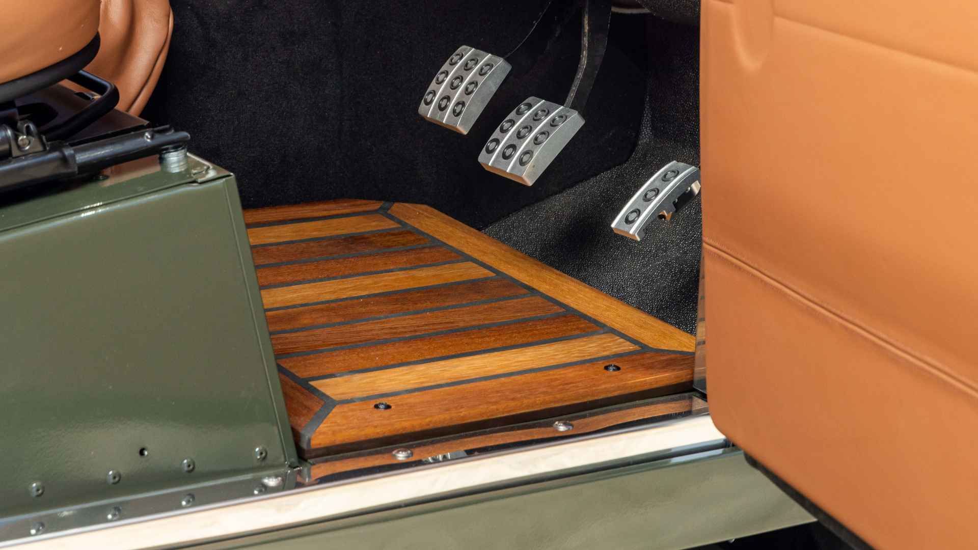 Iroko wood flooring fitted to a Defender footwell, with brake and clutch pedals visible above.