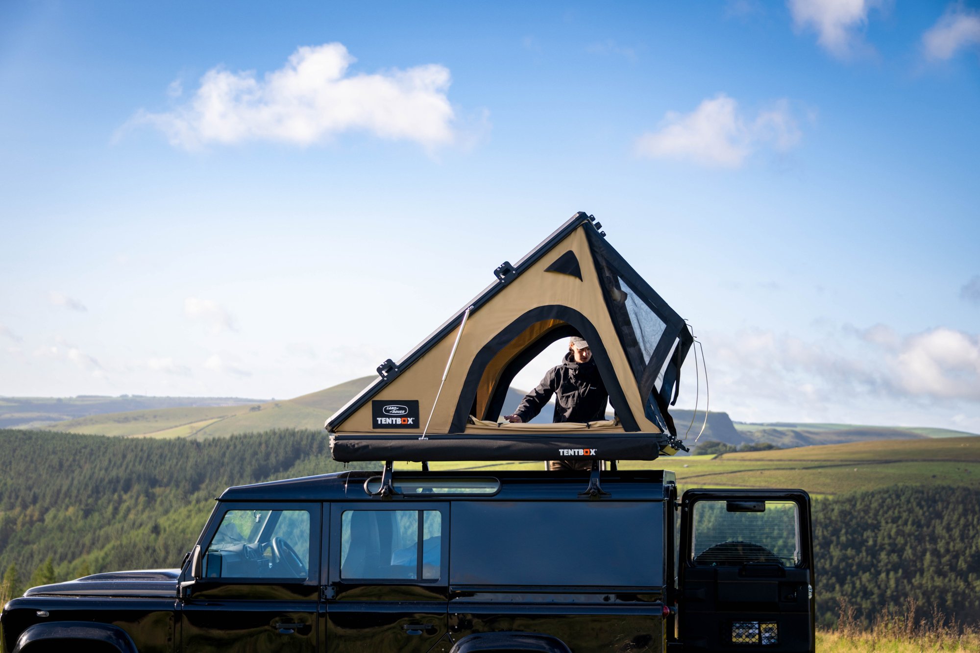 TentBox Cargo, Land Rover edition, open on a Land Rover Defender 110 with rolling moorland in the background and blue skies